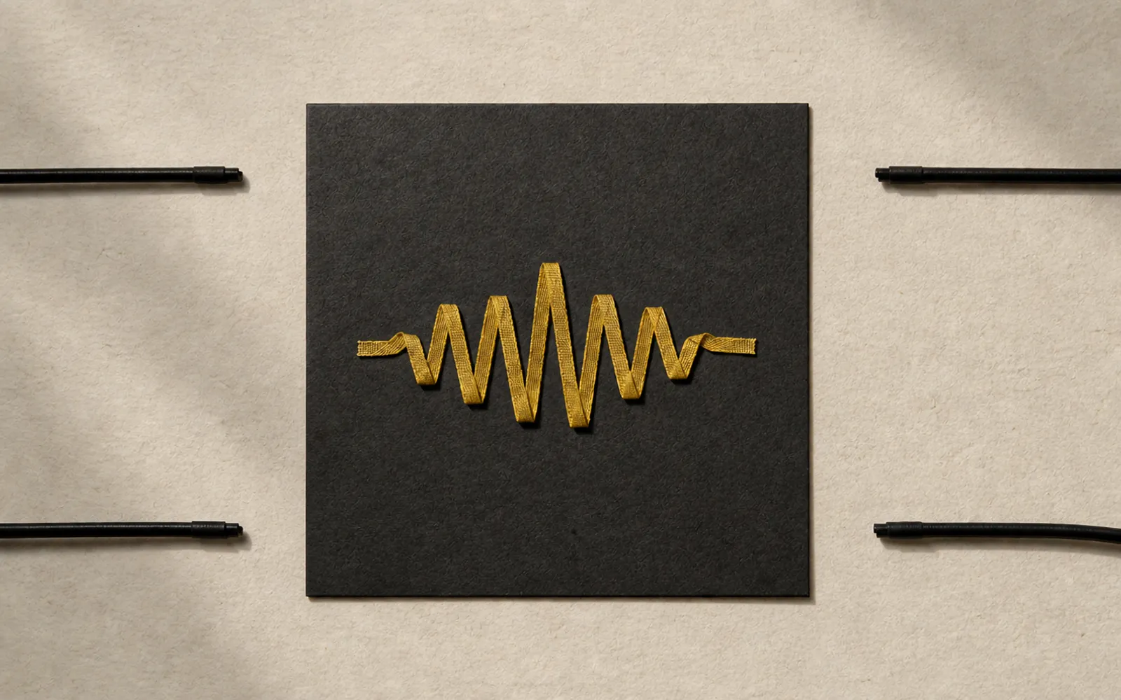A gold audio ribbon contained inside a black square while external cords stop short of its edge